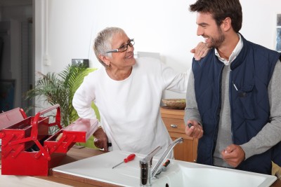 Plumber stops installing a sink to talk with a customer